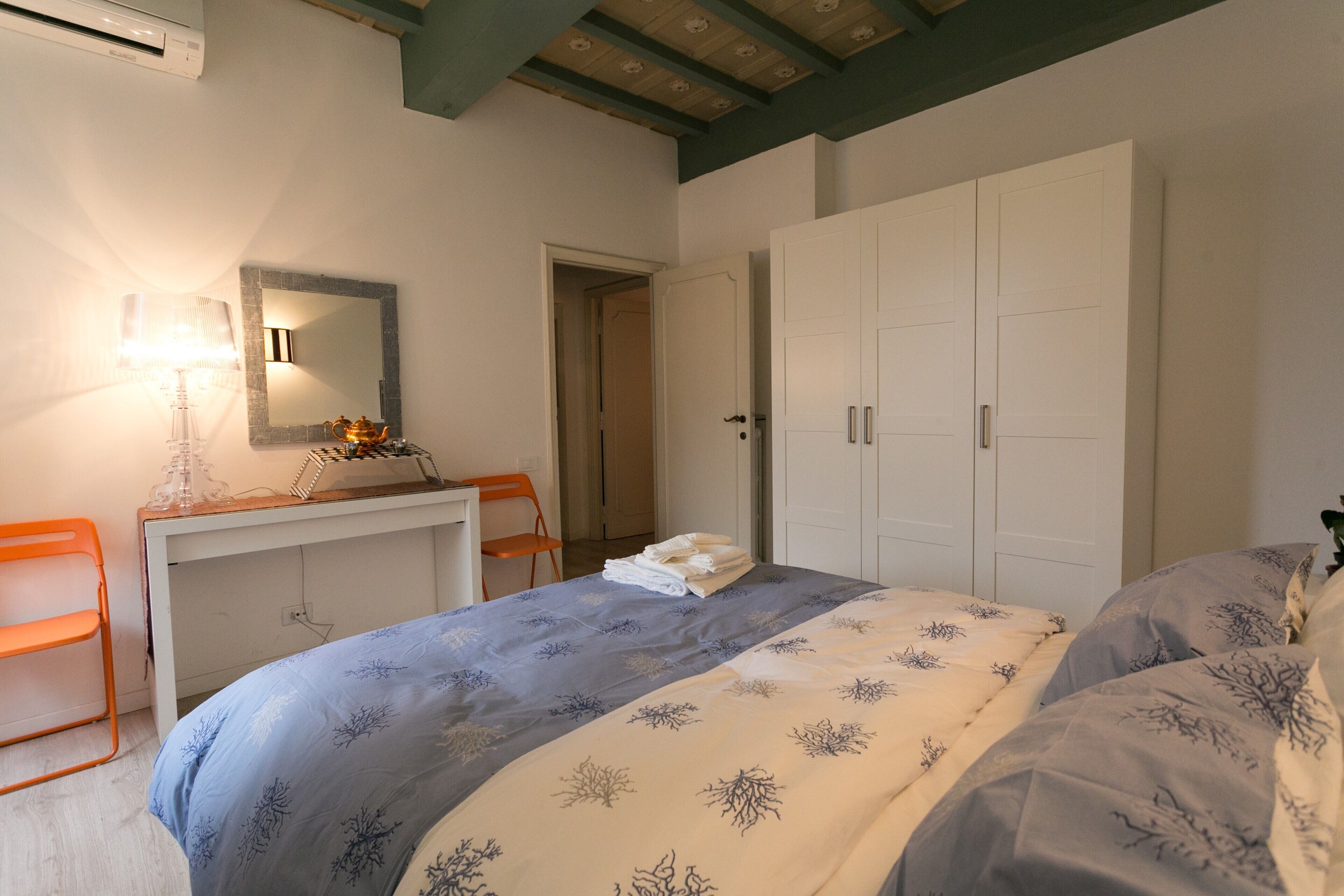 A bedroom with a bed, a desk, a chair, a wardrobe, and a mirror.