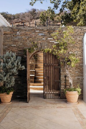 A stone staircase with a wooden door leading to a room. -  Andros Cyclades, private tennis & basketball courts,horses for riding (Chora Andros)