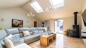 A spacious living room with a large grey sofa, wooden coffee table, and a black fireplace.
