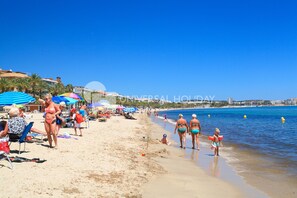 A beach with umbrellas, people, and a clear sky.
