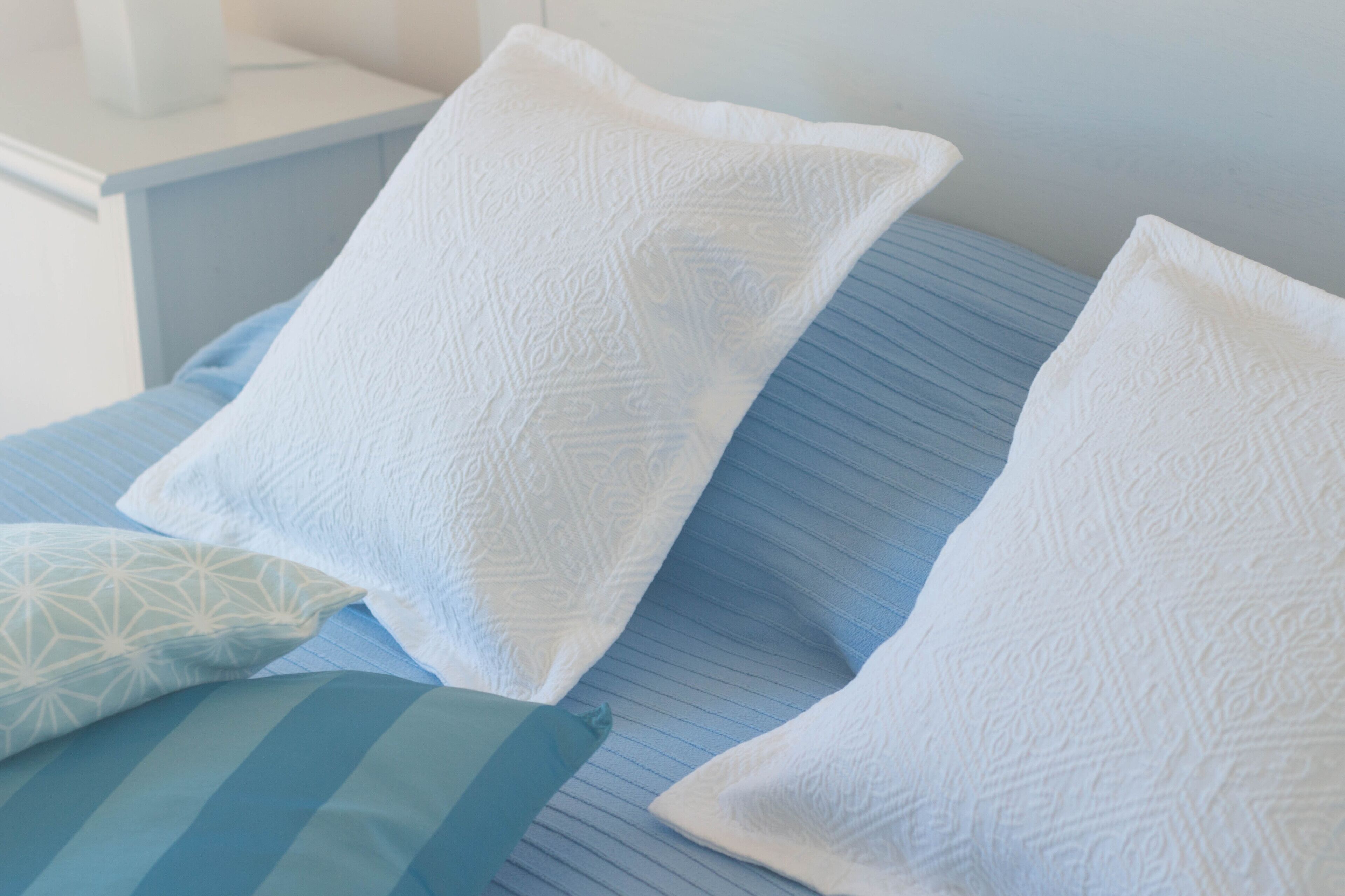 Ein Bett mit blauer Bettwäsche und weißen Kissen.