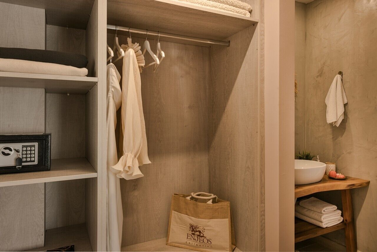 A bathroom with a wooden vanity, a towel rack, and a storage unit with hanging clothes.