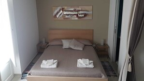 Et hotelværelse med en seng, et billede på væggen og en aircondition.