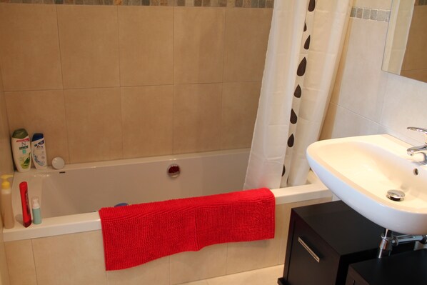 A bathroom with a bathtub, a white sink, and a mirror.