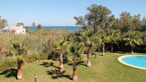 A pool surrounded by palm trees and a grassy area with a view of the sea. - Beachside new luxury apartment with sea & mountain views, great location & Wi-FI (Dénia)