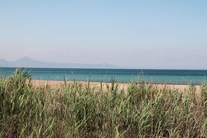 A beach with clear water and distant mountains.