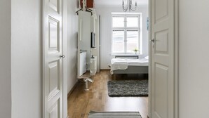 A narrow hallway leading to a bedroom with a bed, a radiator, and a window. - 2ndhomes Bright Top Floor Studio in Fredrikinkatu (Helsinki)