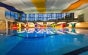 A large indoor swimming pool with a modern design, multiple lanes, and a variety of colorful seating areas around the perimeter. - Modern, spacious apartment - 250m from town centre, 300m from ski lifts (Zell am See)