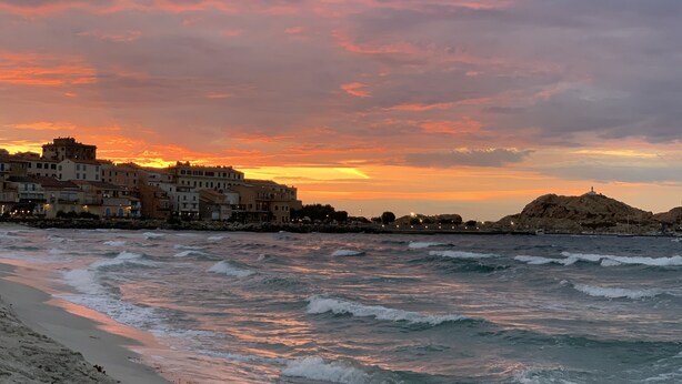 A coastal town at sunset with buildings along the shore and waves crashing onto the beach. - Beautiful villa with sea view and Ile Rousse (Monticello)