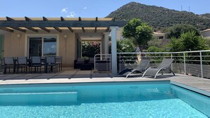 A pool area with lounge chairs, a covered seating area, and a view of a mountain. - Beautiful villa with sea view and Ile Rousse (Monticello)