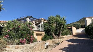 A residential area with a stone wall, a pergola, and a palm tree. - Beautiful villa with sea view and Ile Rousse (Monticello)