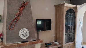 Ein Wohnzimmer mit Kamin, einem an der Wand montierten Fernseher und einem Schrank mit Glastür.