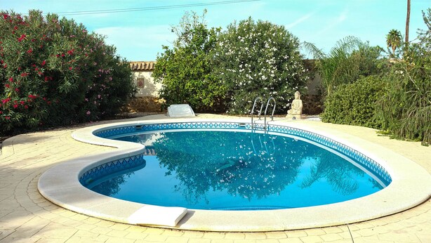 Ein kreisförmiger Pool mit blauer Innenseite, umgeben von einer gepflasterten Terrasse.