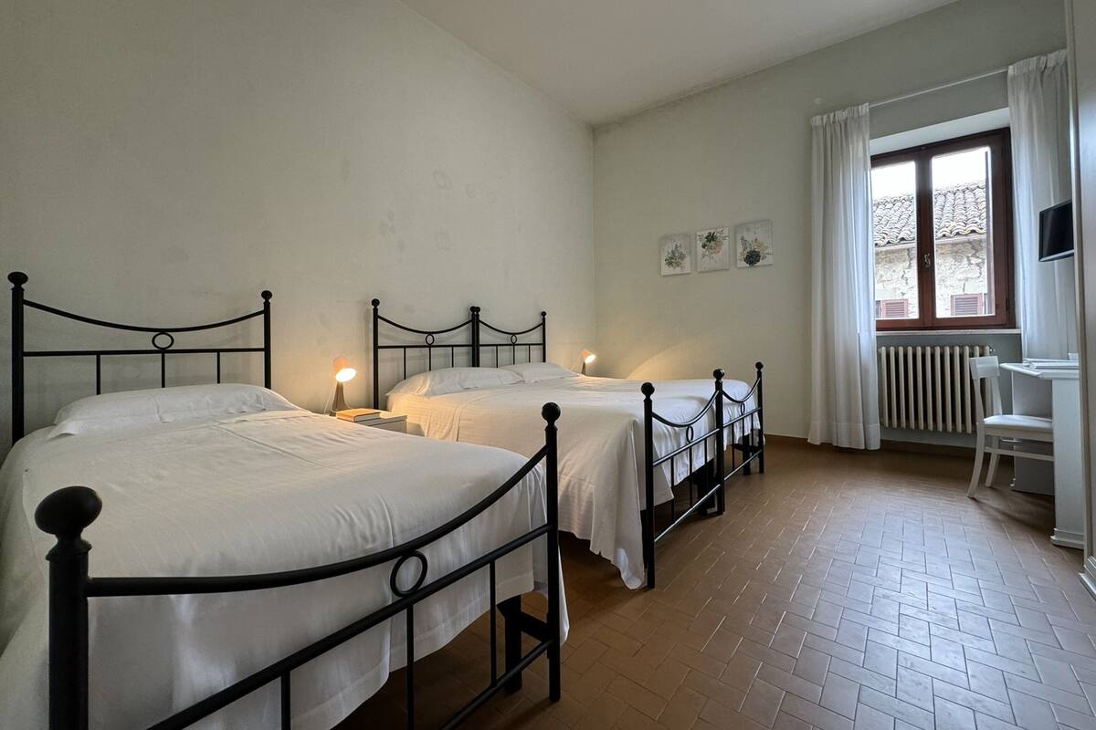A room with three single beds, a desk, and a chair.