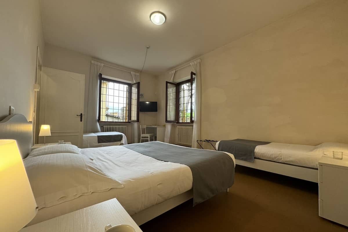 A hotel room with two beds, a desk, a chair, and a TV.