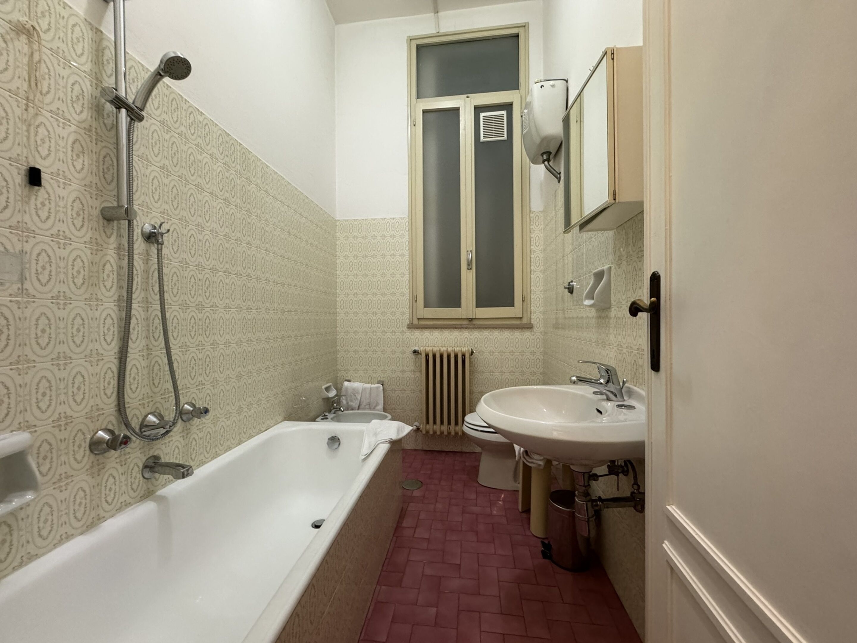 A bathroom with a bathtub, two sinks, a window, and a radiator.