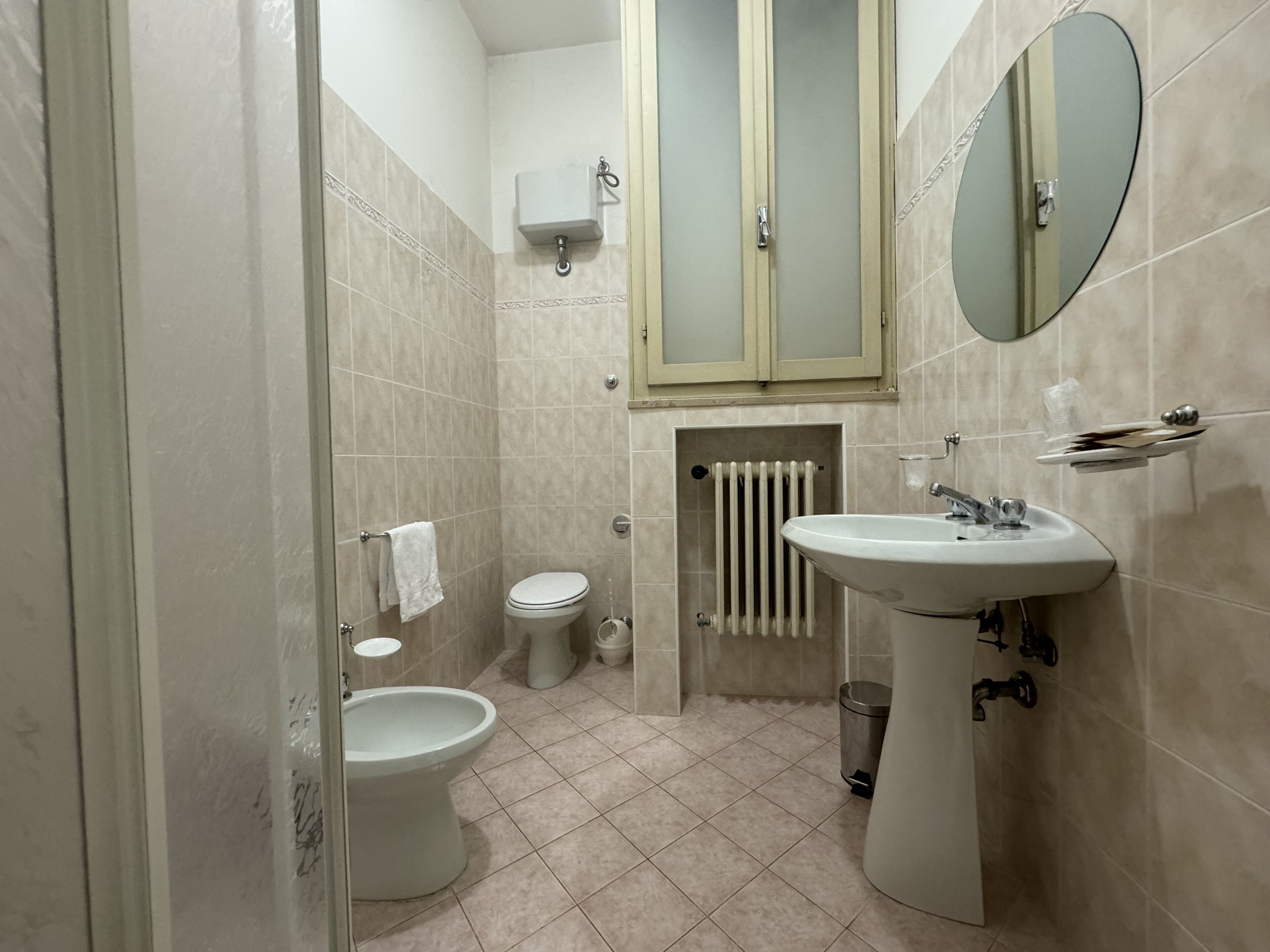 Un baño con inodoro, bidé, lavamanos y espejo.