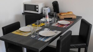 Una mesa de comedor dispuesta con platos, cubiertos, vasos y una hogaza de pan.