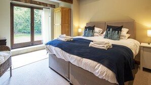 Un dormitorio con una cama grande, un armario de madera y un ventanal corredero que da a un jardín.