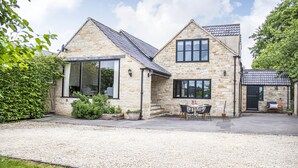 Una casa de piedra con camino de grava y un patio con mobiliario exterior.