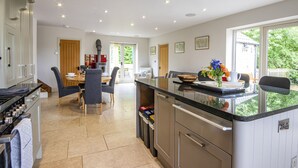 Una cocina moderna con comedor, que incluye una isla central, electrodomésticos integrados y vistas al exterior.