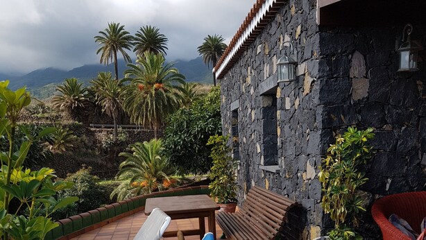 A patio with lounge chairs, a wooden table, and potted plants. - Very cozy stone house (Breña Alta)