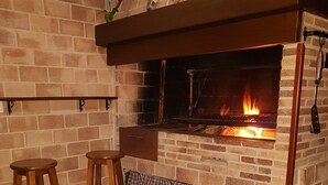 A brick fireplace with a fire, two wooden stools, and a checkered cloth. - Very cozy stone house (Breña Alta)