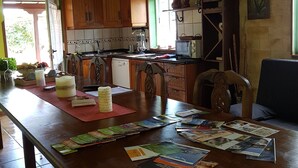 A kitchen with wooden cabinets, a dining table with magazines, and a television above the counter. - Very cozy stone house (Breña Alta)