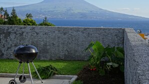 A barbecue grill on a patio with a view of a mountain and the sea. - Luxury  Repouso do Milhafre 181/AL (Horta)