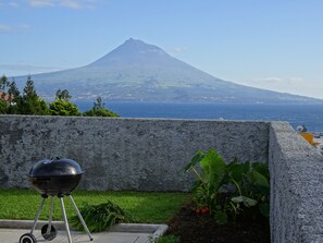 Una parrilla en un patio con vistas a una montaña y al mar.
