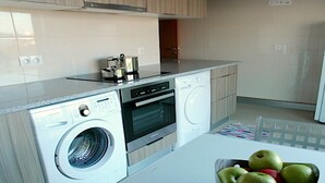 A modern kitchen with a washing machine, oven, and a refrigerator. - Luxury  Repouso do Milhafre 181/AL (Horta)