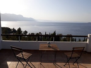 A balcony with a view of a large body of water and distant mountains. - A modern villa in a unique setting with stunning views. The real Greece. (Metamorfosi)