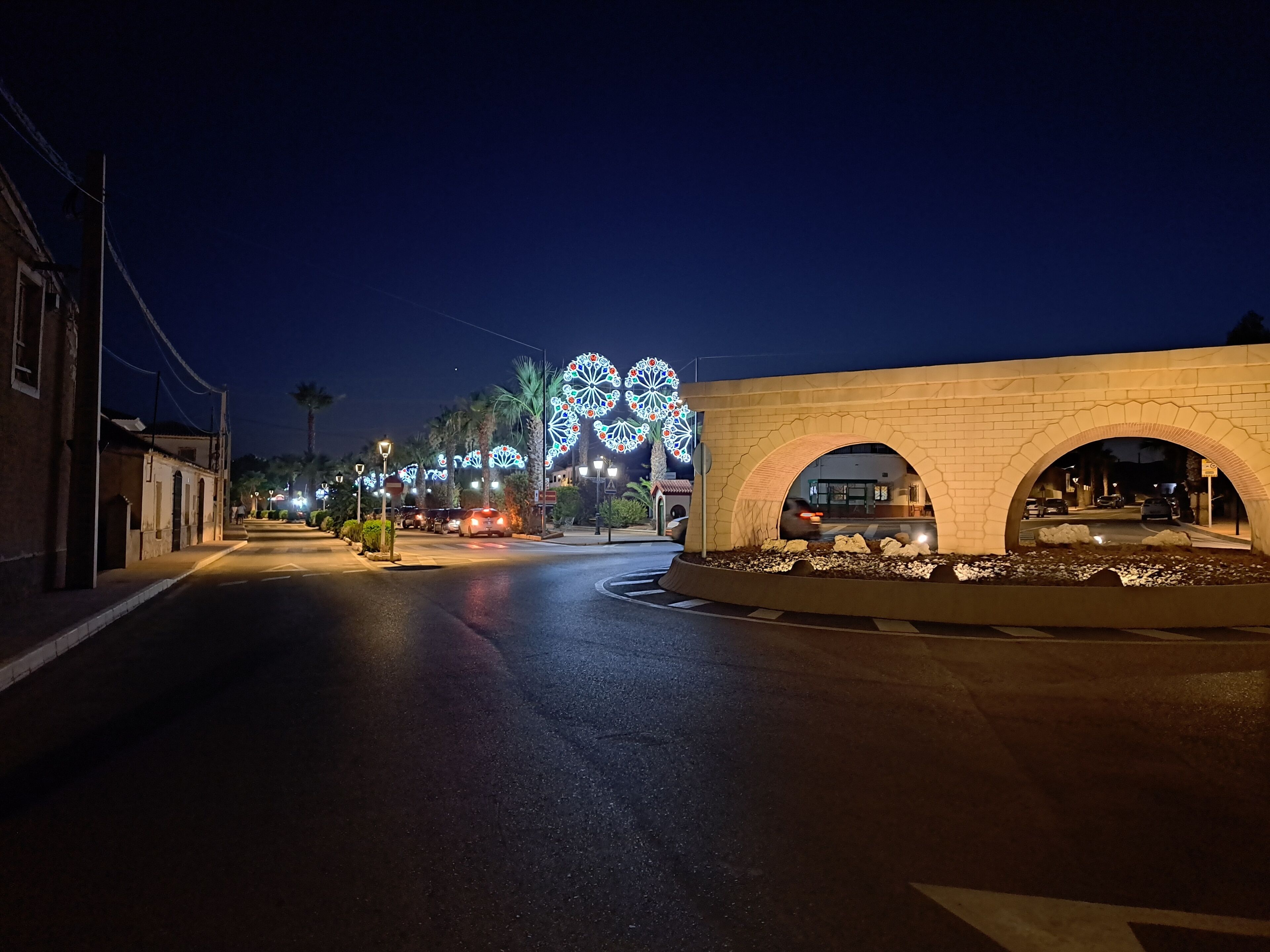 Una strada di notte con un arco in mattoni e luci decorative.