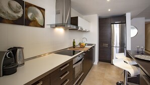 A modern kitchen with a stainless steel range hood, a built-in oven, and a double sink.