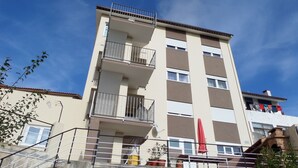 A multi-story building with balconies, a red umbrella, and potted plants. - Rental House 12Om² - 8 people - Figueira da Foz (Buarcos)