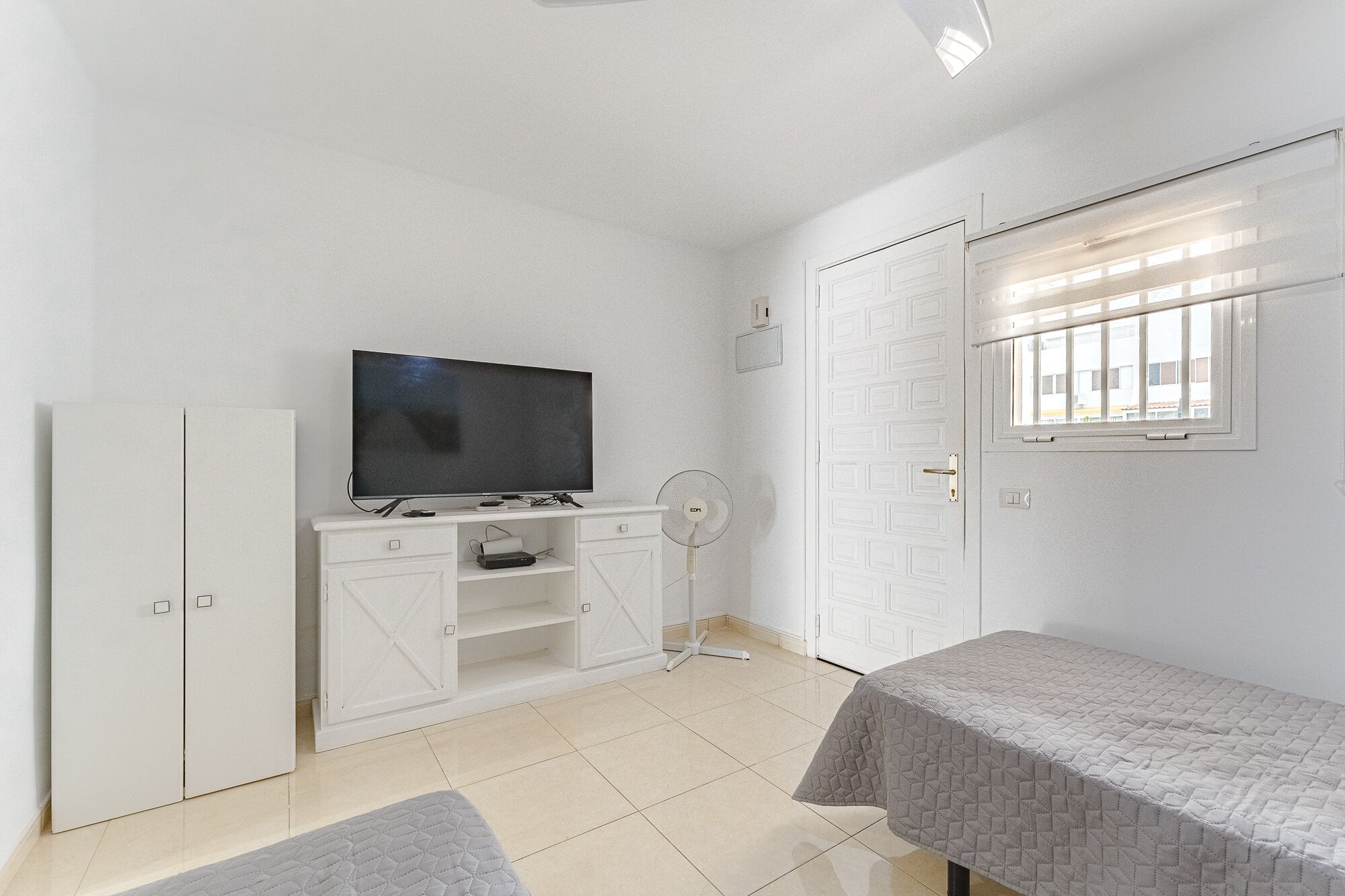 A bedroom with a TV, wardrobe, and a bed.