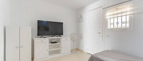 A bedroom with a TV, wardrobe, and a bed.
