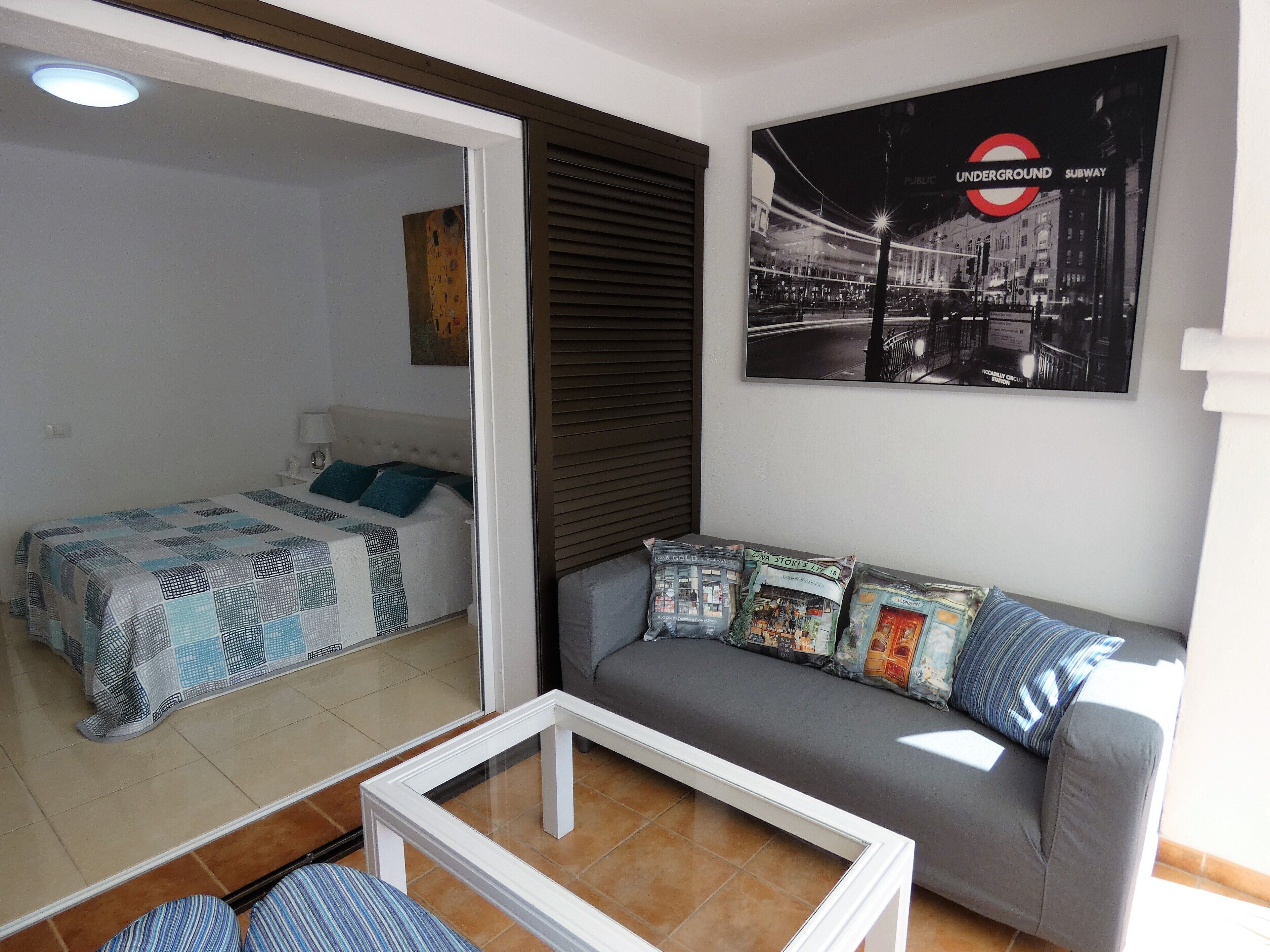 Ein Schlafzimmer mit einem Bett, einem Schlafsofa, einem Couchtisch und einem Poster der London Underground.