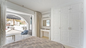 A bedroom with a large bed, a wardrobe, a vanity with a mirror, and an open balcony with a view of palm trees and a building. - Beautiful apartments  with large terrace close to the beach (Arona)