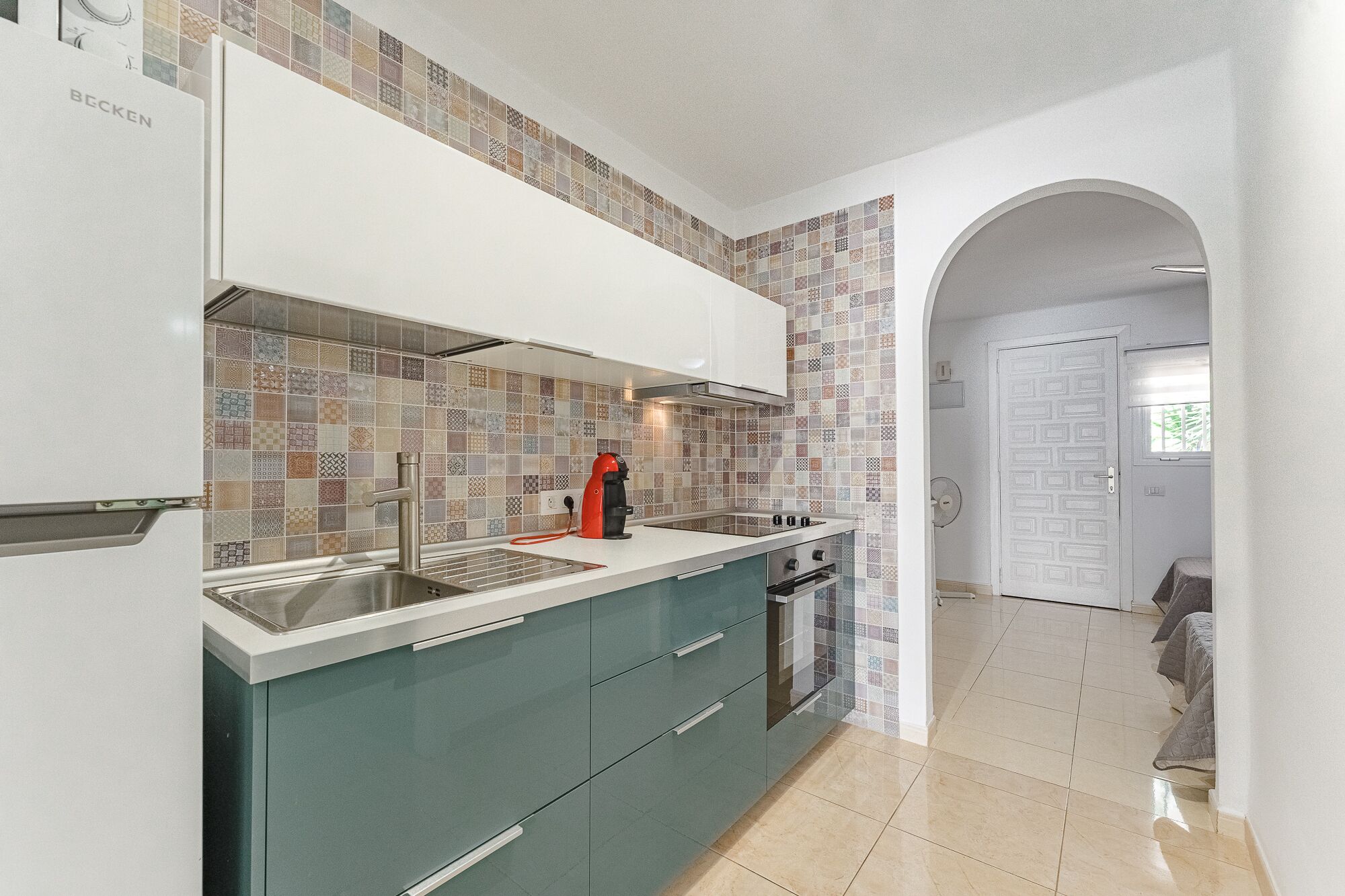 Una cocina moderna con salpicadero de azulejos, electrodomésticos de acero inoxidable y vistas al comedor.
