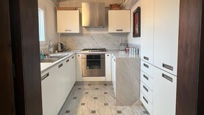 A kitchen with white cabinets, a central island, a stove, and a tiled floor. - Stylish apartment 5 min walk from Rialto 360 degree panoramic view (venice)