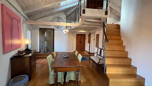 A spacious dining area with a wooden table and chairs, a staircase, and a loft with a workbench. - Stylish apartment 5 min walk from Rialto 360 degree panoramic view (venice)