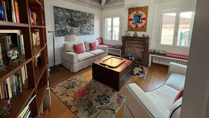 A cozy living room with a fireplace, a sofa, a coffee table, and a bookshelf. - Stylish apartment 5 min walk from Rialto 360 degree panoramic view (venice)