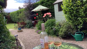 Ein Garten mit Tisch, einer Weinflasche und zwei Gläsern.