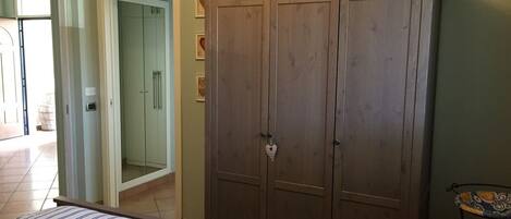 A bedroom with a bed, a wardrobe, and a small table.