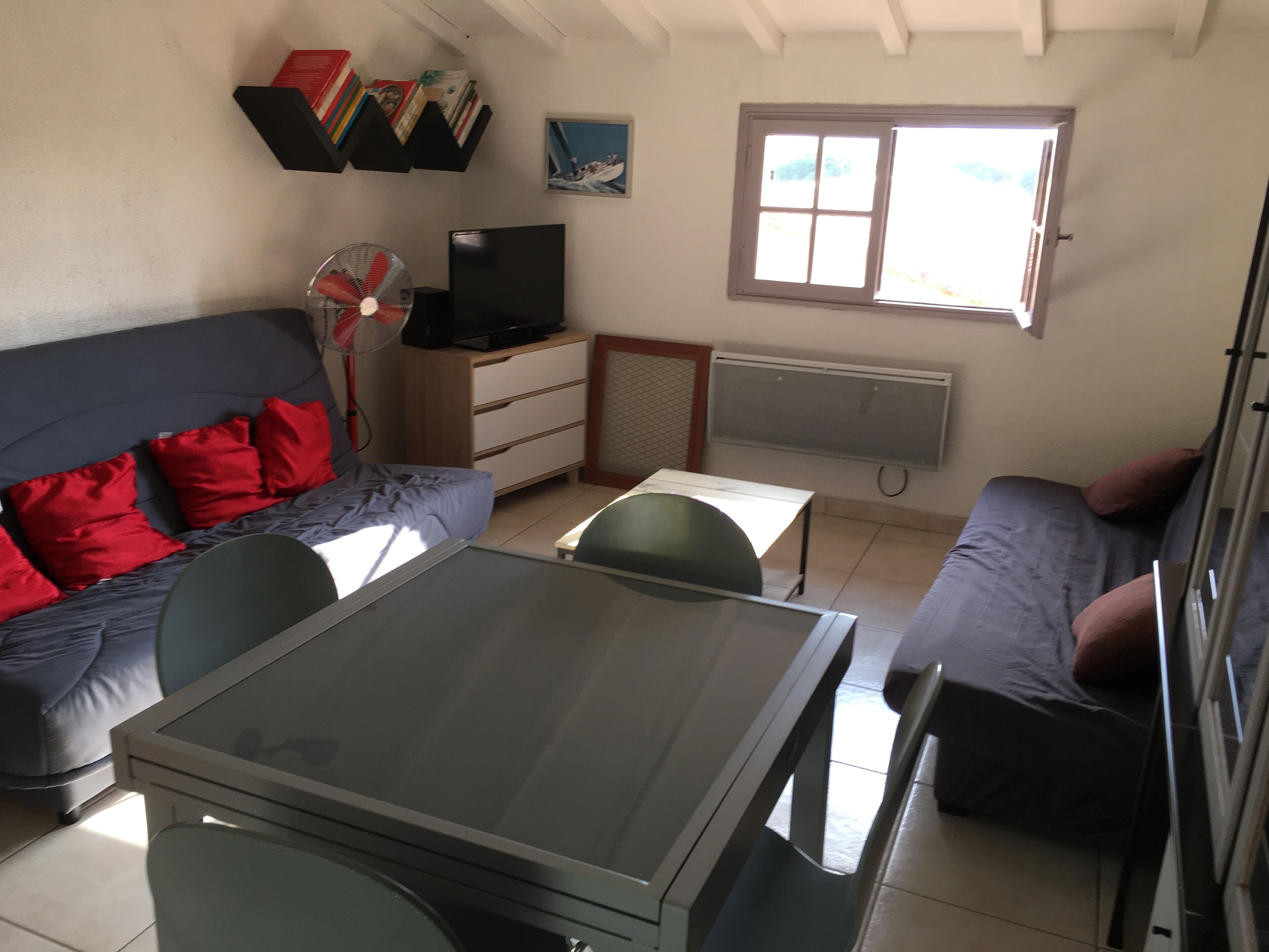 Un espacio habitable compacto con sofá, una mesita, televisor y ventana.