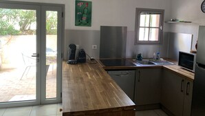 Una cocina con encimera de madera, cafetera, lavavajillas y ventana.