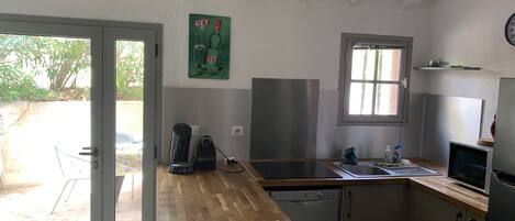 Una cocina con encimera de madera, cafetera, lavavajillas y ventana.