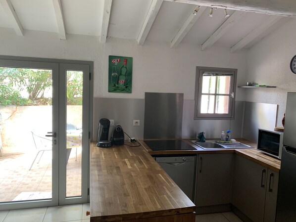 A kitchen with a wooden countertop, a coffee maker, a dishwasher, and a window.