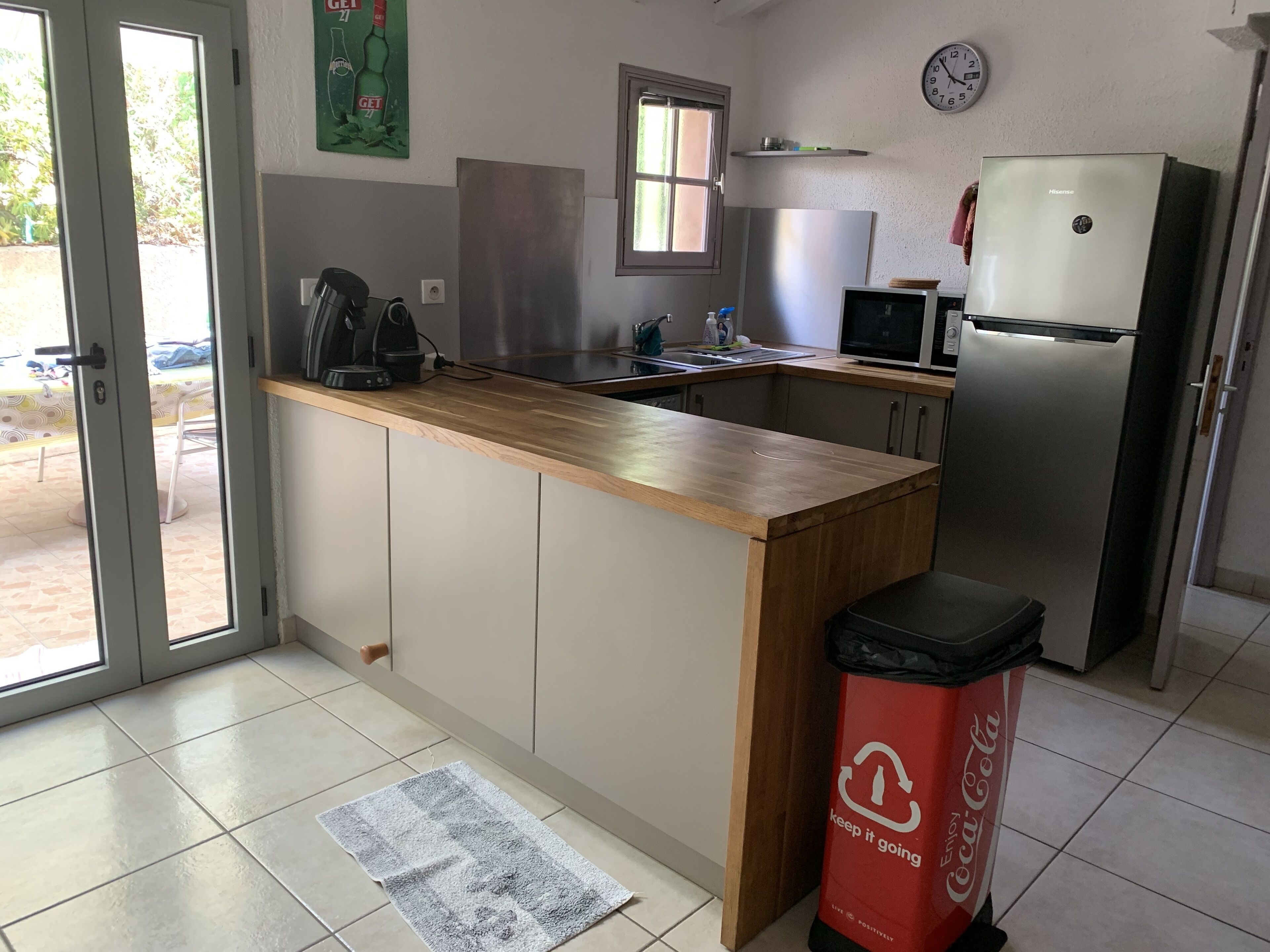 A kitchen with a wooden countertop, stainless steel appliances, a microwave, and a refrigerator.